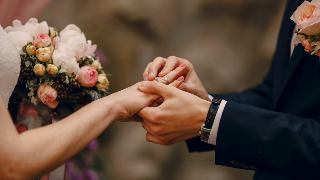 Man putting a ring on a the woman's hand.