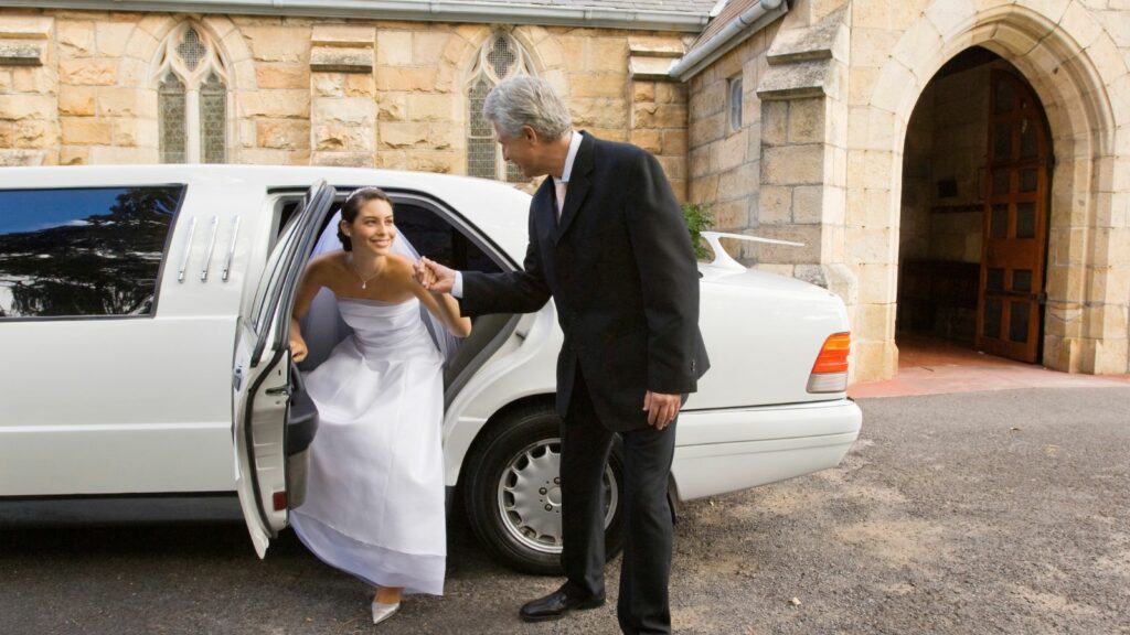 Driver helping the bride to get out of the limousine.