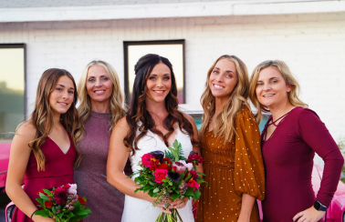 Bridal Party of five stands in front of Pink Cadillacs looking into the camera.