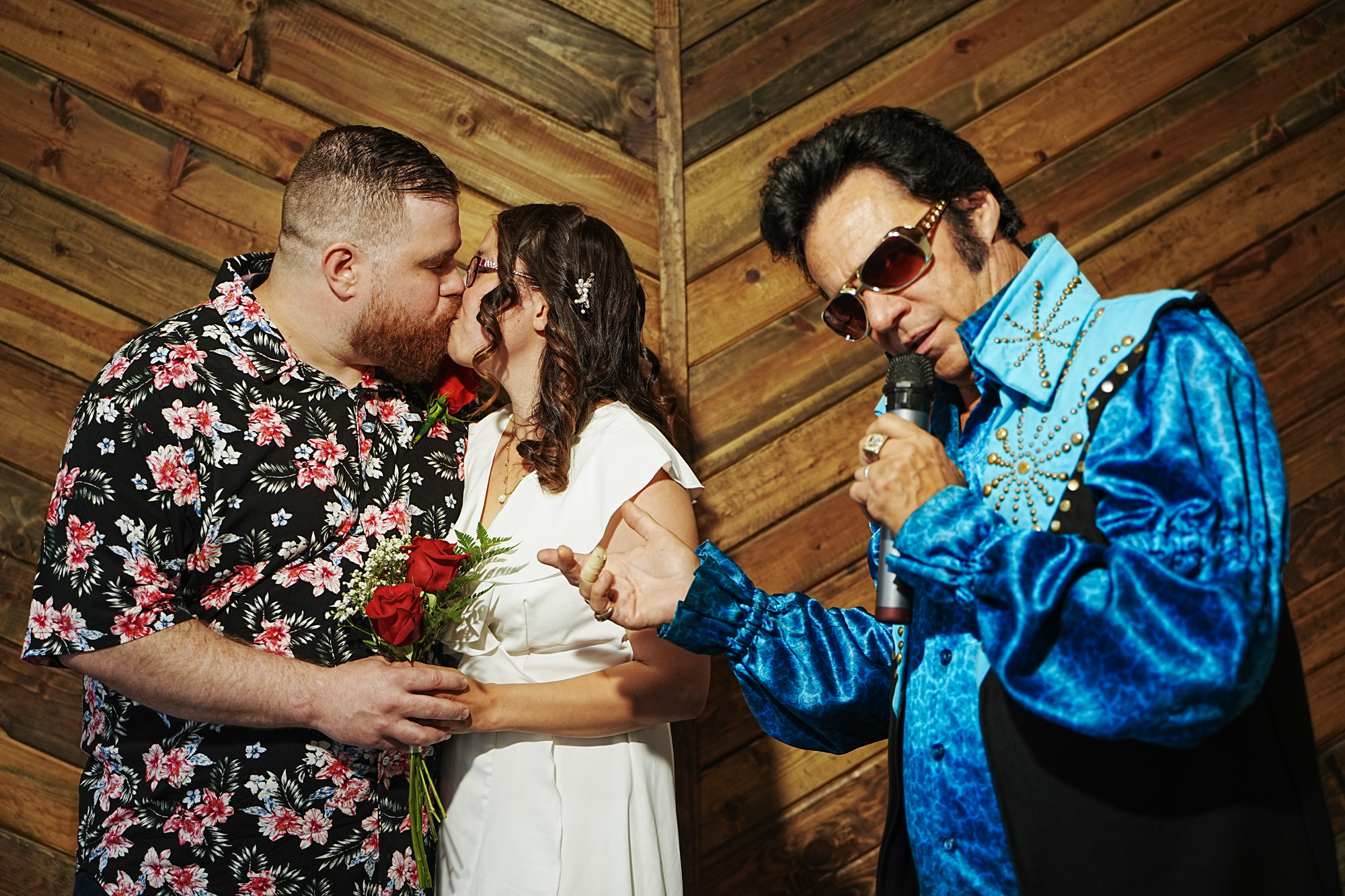 Elvis Presley impersonator with a couple kissing on camera