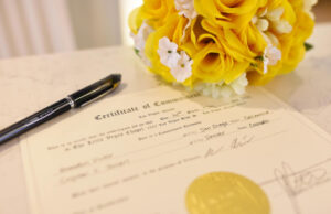 A marriage license with a yellow bouquet and a pen