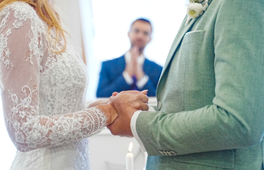 A cropped image of bride and groom at the altar with a Minister in the background