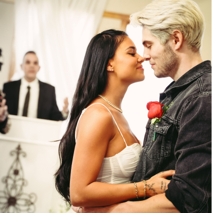 An out of focus image of a Minister with the groom attempting to kiss the bride in front of altar