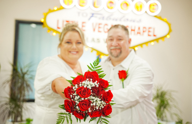 An out of focus image of bride and groom at The Little Vegas Chapel with an elegant red roses bouquet