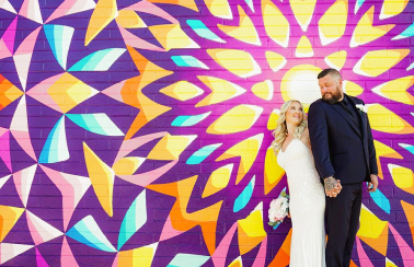 A couple in front of camera with an abstract and colorful backdrop
