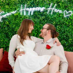A groom sitting on a couch carrying his bride posing for a photo