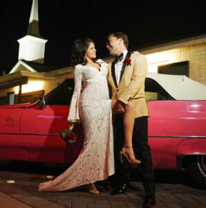 An evening photoshoot of a couple posing in front of pink cadillac
