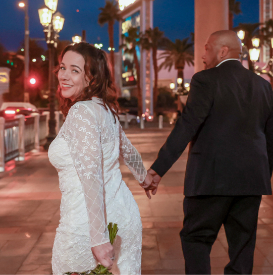 Pretentious bride and groom holding hands posing for a photo