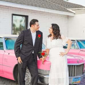 Bride and groom posing for shoot with a pink cadillac