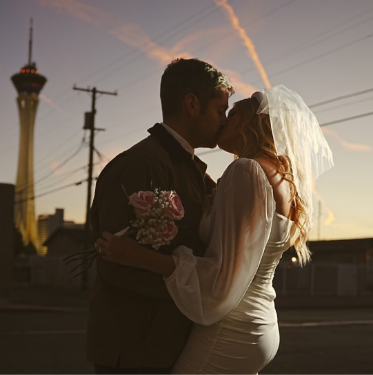Bride and groom kissing for a photo with a sunset backdrop